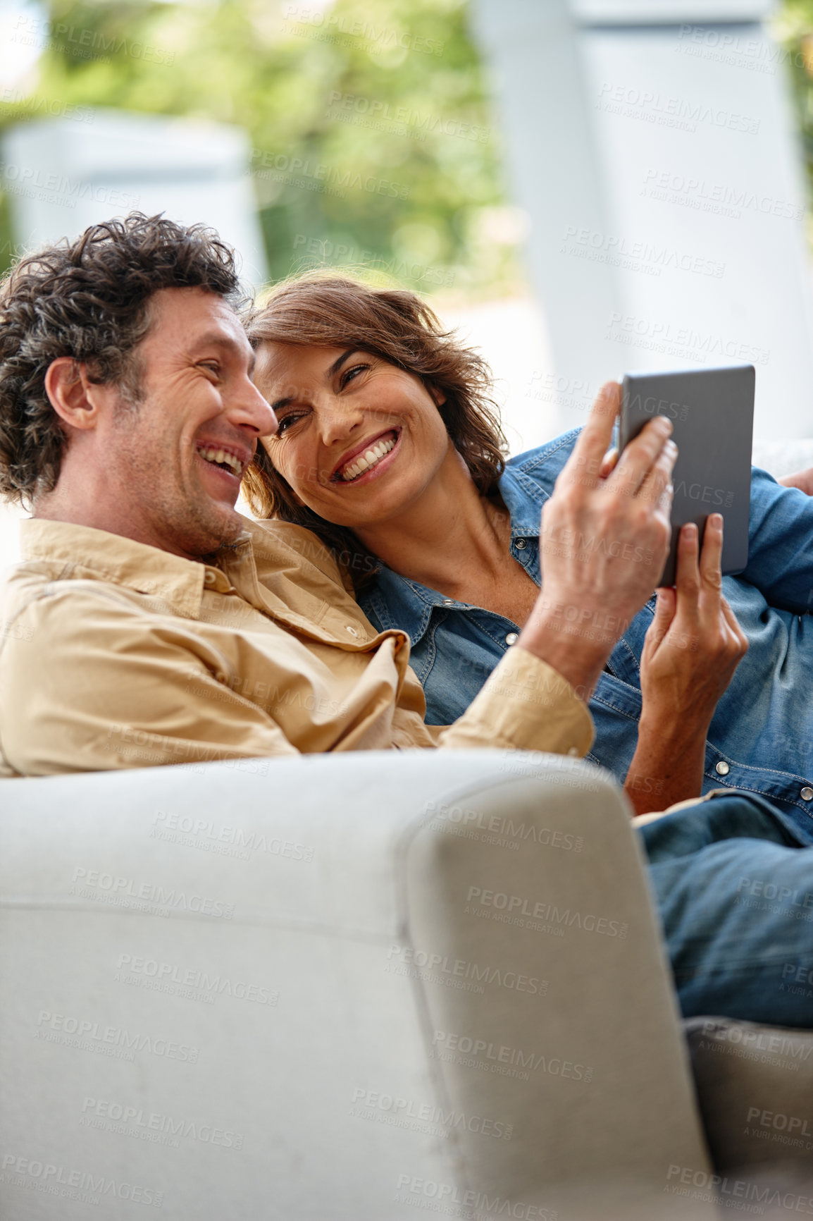 Buy stock photo Shot of a husband and wife using a digital tablet together at home