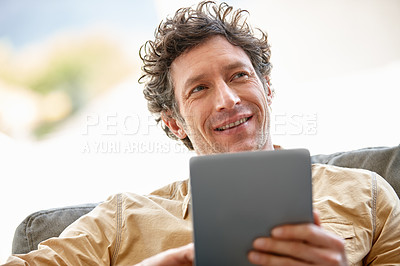 Buy stock photo Shot of a mature man using a digital tablet on the sofa at home