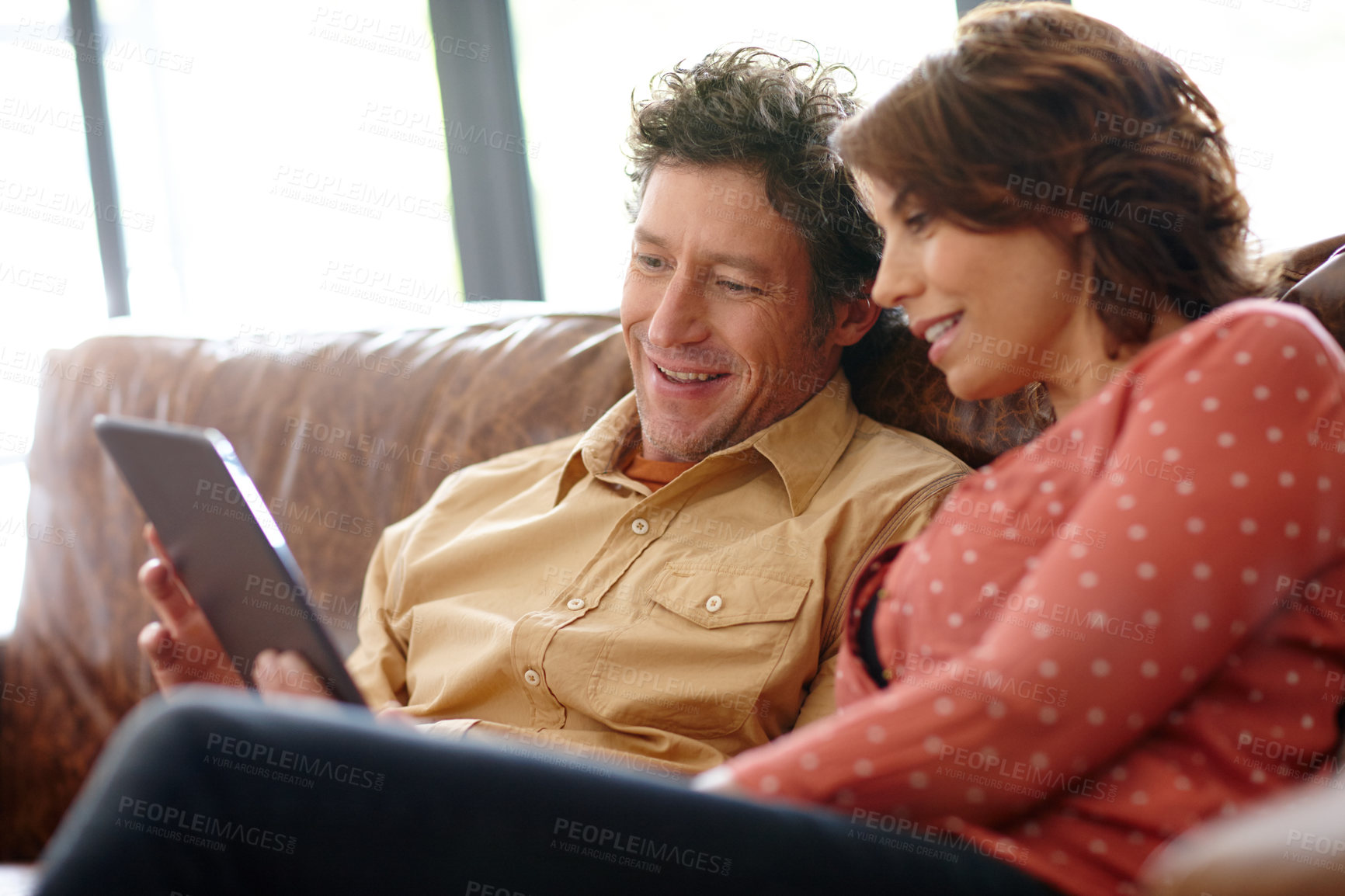 Buy stock photo Shot of a husband and wife using a digital tablet together at home