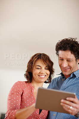 Buy stock photo Shot of a husband and wife using a digital tablet together at home