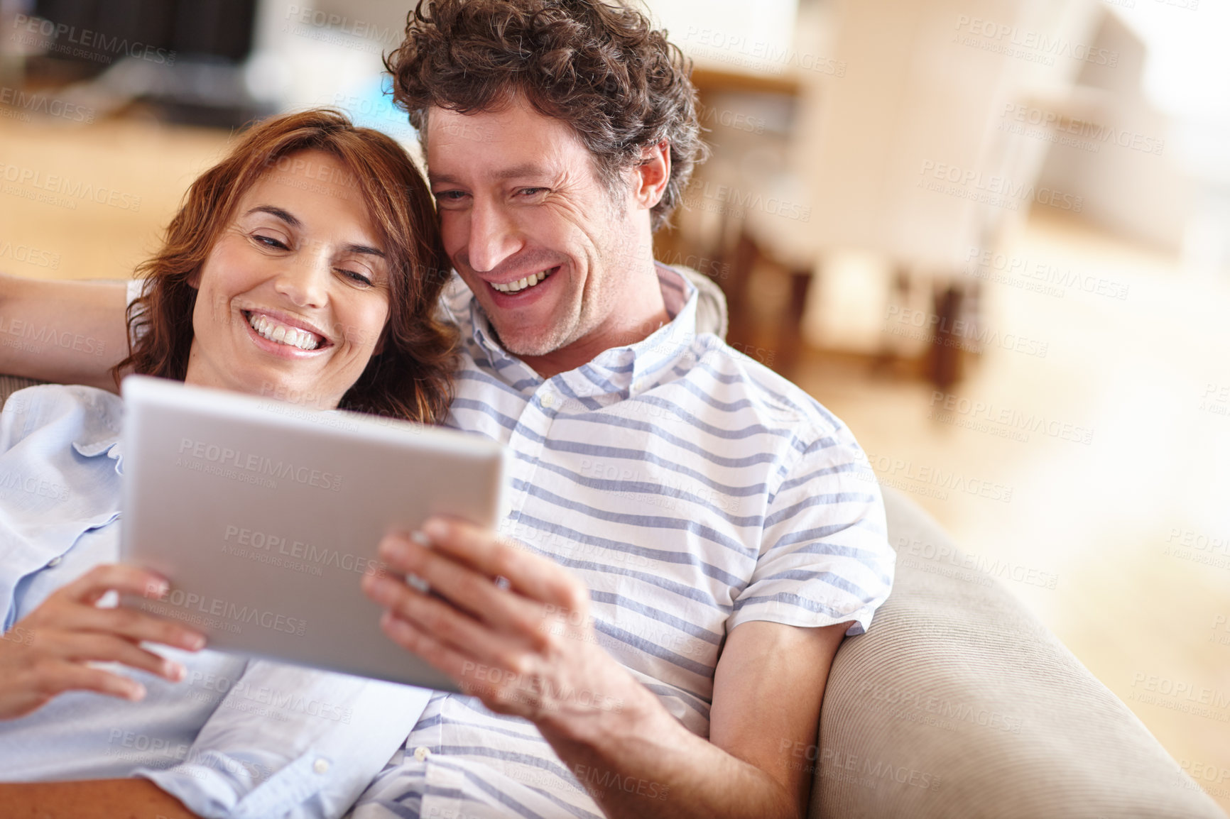 Buy stock photo Shot of a husband and wife using a digital tablet together at home