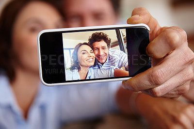 Buy stock photo Cropped shot of a husband and wife taking a selfie together on a smartphone