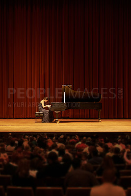 Buy stock photo Shot of a young woman playing the piano during a musical concert