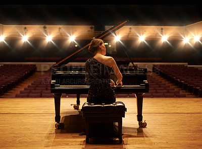 Buy stock photo Shot of a young woman playing the piano during a musical concert