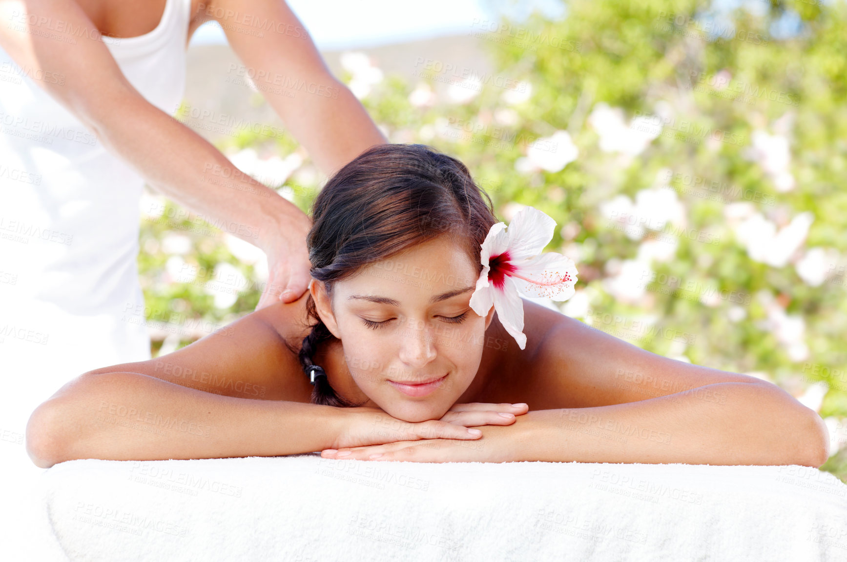 Buy stock photo Back massage, flower and woman at spa for health, skincare or calm for wellness outdoor. Masseuse, peace and girl at luxury salon with natural hibiscus for therapy service, relax and beauty treatment