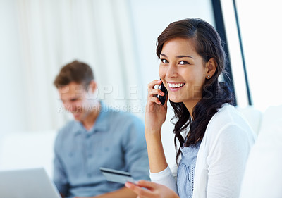 Buy stock photo Happy woman using phone and credit card with man using laptop in background