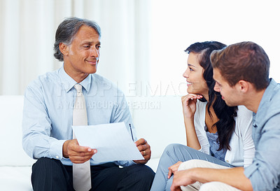 Buy stock photo Mature advisor explaining financial plan to young couple at home