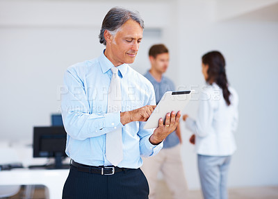 Buy stock photo Portrait of mature business man using electronic tablet with colleagues in background