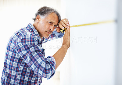 Buy stock photo Handsome mature architect measuring wall with masking tape