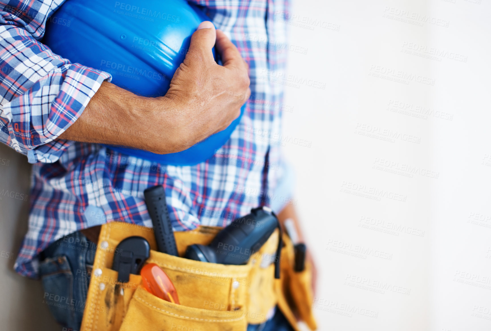 Buy stock photo Mid section of construction worker with tool belt holding blue protective helmet