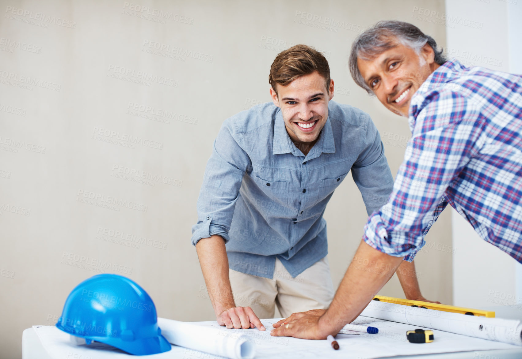 Buy stock photo Portrait of happy young man reviewing blueprint with contractor