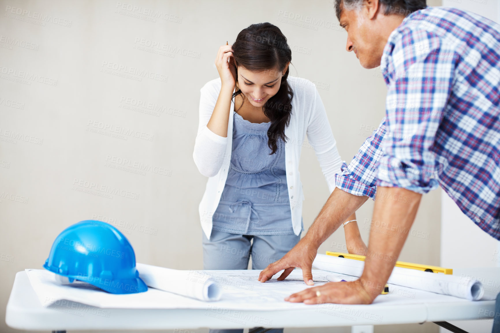 Buy stock photo Happy young woman smiling while discussing home renovation plans with architect over blueprint
