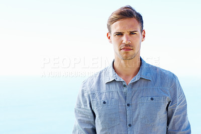 Buy stock photo Portrait, serious and man by ocean for vacation, travel and fashion for summer or holiday. Beach, male person and water or sea in nature or Greece with style, shirt and trendy outfit for morning