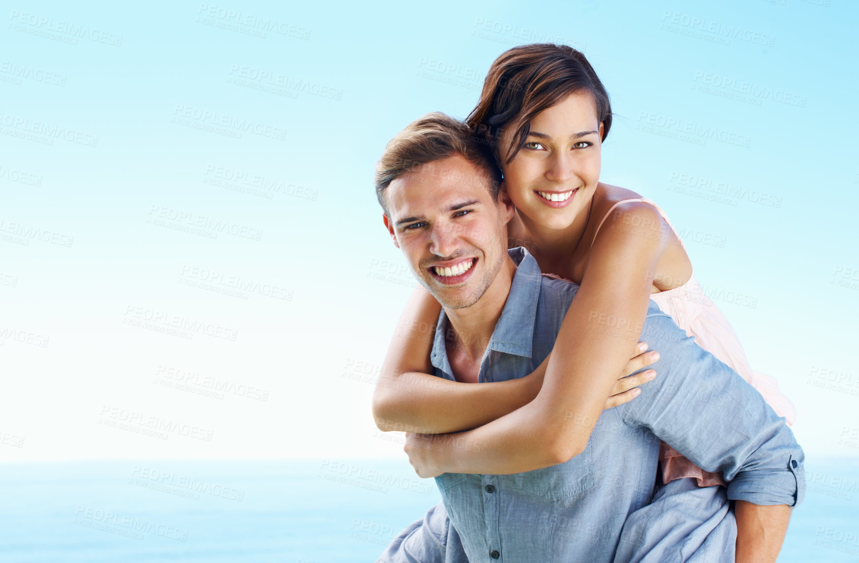 Buy stock photo Ocean, couple and happy with piggyback for bonding with love, trust and support in Spain. People, relationship and smile on portrait for care on holiday or vacation for honeymoon, relax and break
