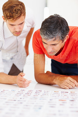 Buy stock photo Two professional photographers checking out photos on table