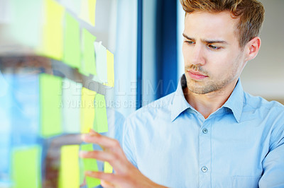 Buy stock photo Handsome business man reading adhesive notes stuck to the glass