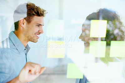 Buy stock photo Business man and woman discussing with adhesive notes stuck on glass