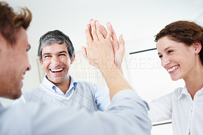 Buy stock photo Shot of a group of young business people hi-fiving each other