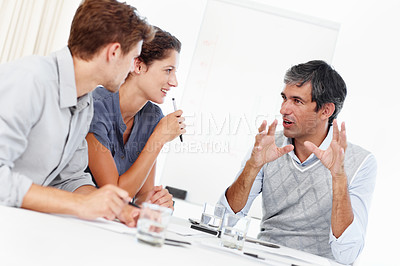 Buy stock photo Shot of three positive-looking businesspeople talking together in a meeting