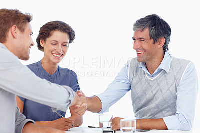 Buy stock photo Shot of two businessmen shaking hands while in a meeting with a female coworker