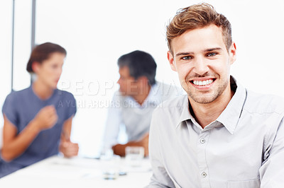 Buy stock photo Closeup portrait of a smiling young businessman with his colleagues sitting in the background