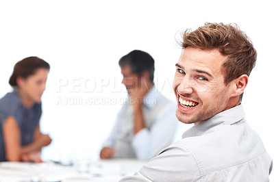Buy stock photo Closeup portrait of a confident young businessman looking over his shoulder with his colleagues sitting in the background