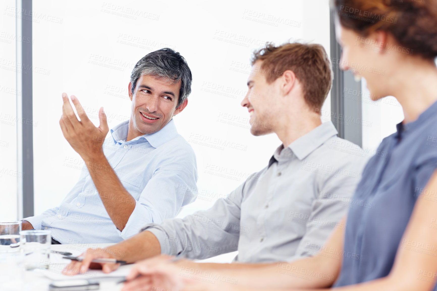 Buy stock photo Shot of three positive-looking businesspeople talking together in a meeting