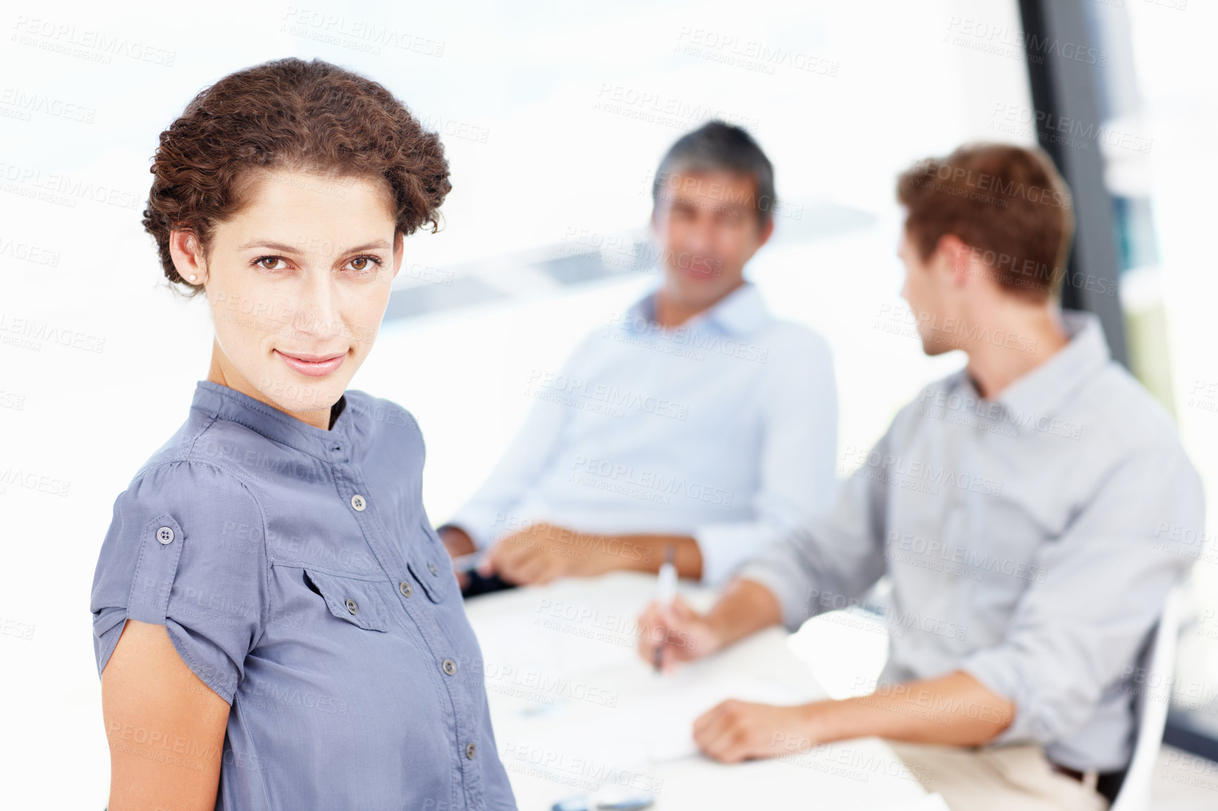 Buy stock photo Portrait of an attractive office worker with her coworkers seated behind her