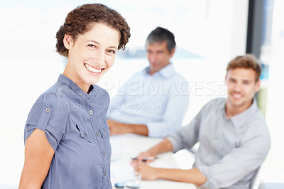 Buy stock photo Portrait of a smiling office worker with colleagues sitting behind her