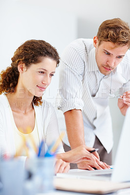 Buy stock photo Two casually dressed business people working on laptop and looking at the screen