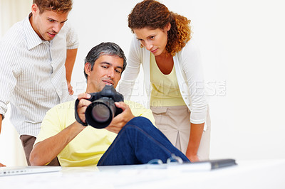 Buy stock photo Male photographer showing pictures to his colleagues in his camera