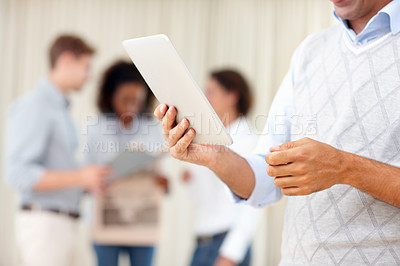 Buy stock photo Business man using tablet PC with colleagues discussing in background