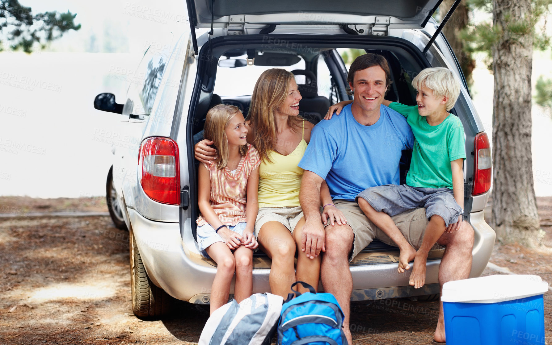 Buy stock photo Happy family of four sitting in the back of a car and enjoying their vacation