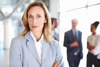 Buy stock photo Portrait of mature business woman with executives discussing in background