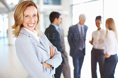 Buy stock photo Portrait of happy mature business woman with associates discussing in background