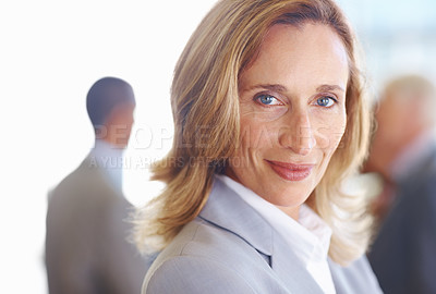 Buy stock photo Closeup of successful mature business woman looking at you with executives in background
