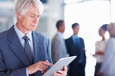 Buy stock photo Portrait of senior male executive using electronic tablet with executives in background