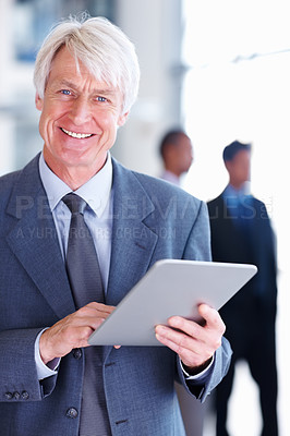 Buy stock photo Portrait of senior male executive using tablet PC with executives in background