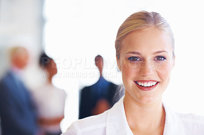 Buy stock photo Closeup of pretty young female executive smiling with business people in background