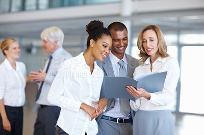 Buy stock photo Portrait of happy multi racial business people looking at documents with executives in background