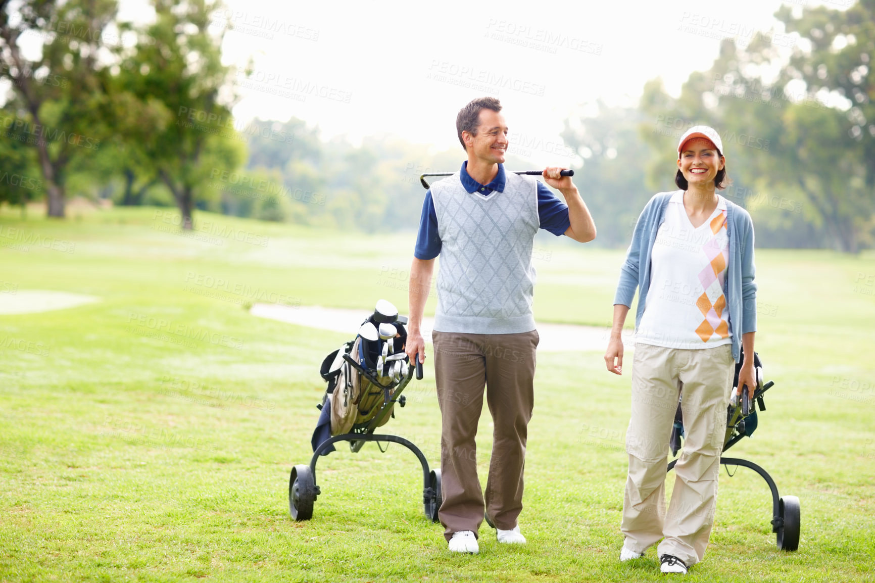 Buy stock photo Happy, walking and couple on golf course for game, outdoor fun and fitness on weekend morning. Love, woman and man on grass for sports date with smile, health and wellness with exercise in nature