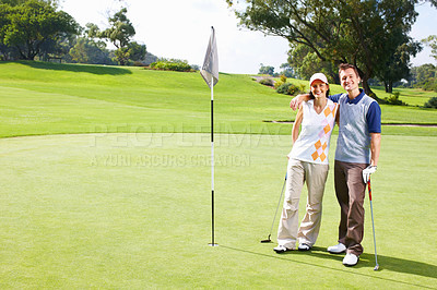 Buy stock photo Full length of golfing couple standing on the putting green with arms around
