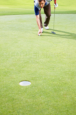 Buy stock photo Male golfer placing the ball on the grass and preparing to putt