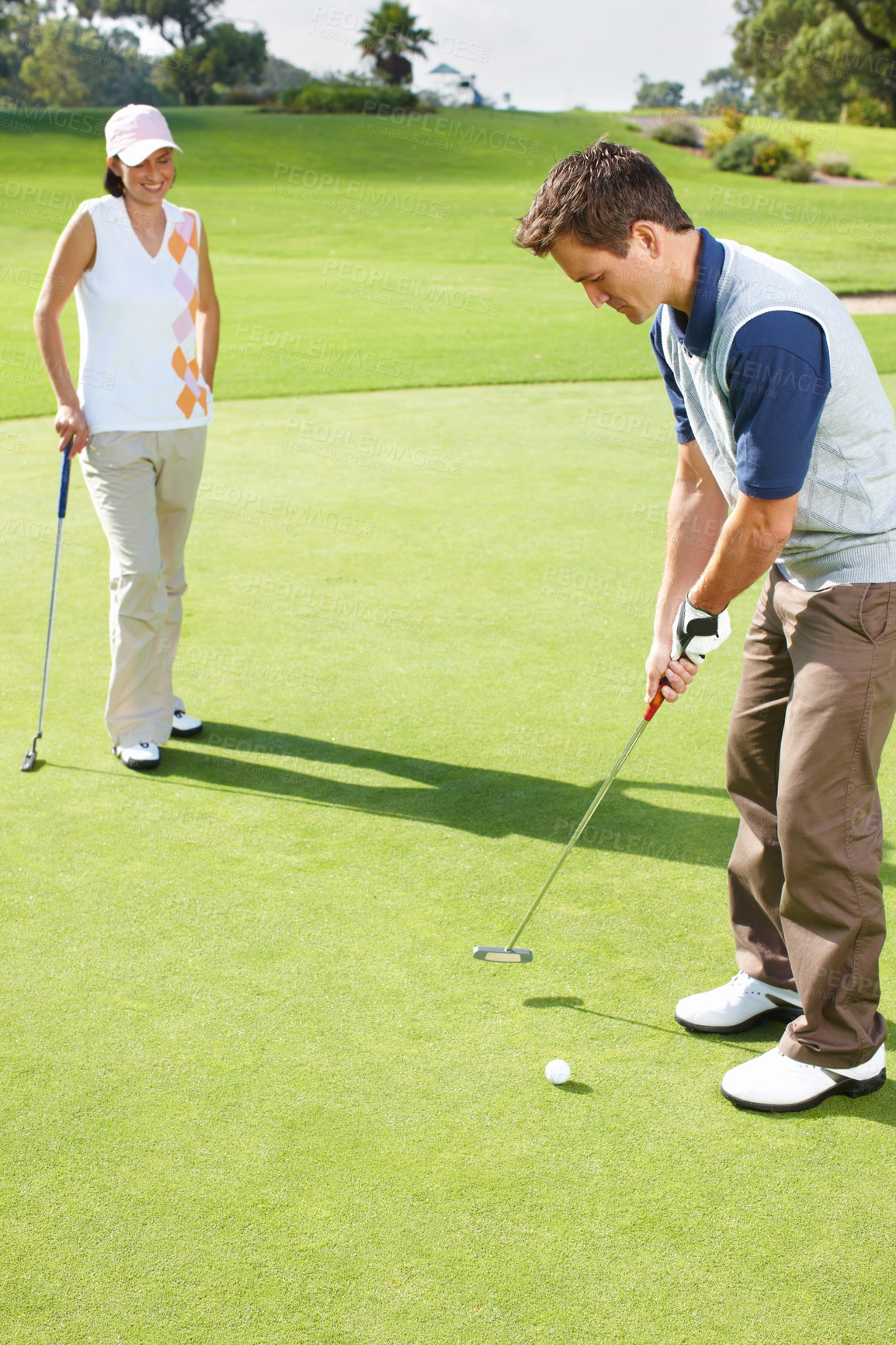 Buy stock photo Young couple playing golf together on the green