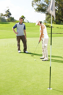 Buy stock photo Hole, coaching and couple on golf course with club, outdoor fun and fitness on weekend morning together. Ball, woman and man on green grass for outdoor sports, challenge and competition with exercise