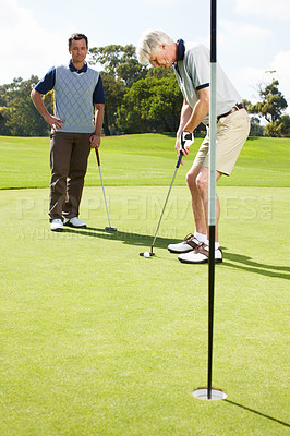 Buy stock photo Two men out on the green playing a round of golf together