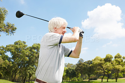 Buy stock photo Senior man following through on his golf swing while on the course