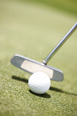 Buy stock photo Golf ball lying on the grass out on the course with a putter getting ready to hit it