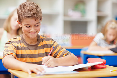 Buy stock photo Writing, school and child in classroom for learning, education and lesson for development. Happy student, academy and young boy with stationery for test, creativity and assignment for knowledge