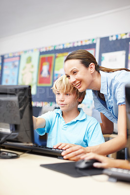 Buy stock photo An attractive young teacher assisting a schoolboy in computer class